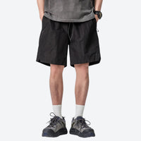 
                  
                    Unisex nylon quick-dry shorts - black quick-dry shorts with gray tee, front standing view, for travel and city walks
                  
                