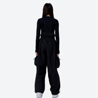 
                  
                    Women's breathable high-waist ski pants with cargo pockets - black cargo snow pants with black top, on-model back view
                  
                